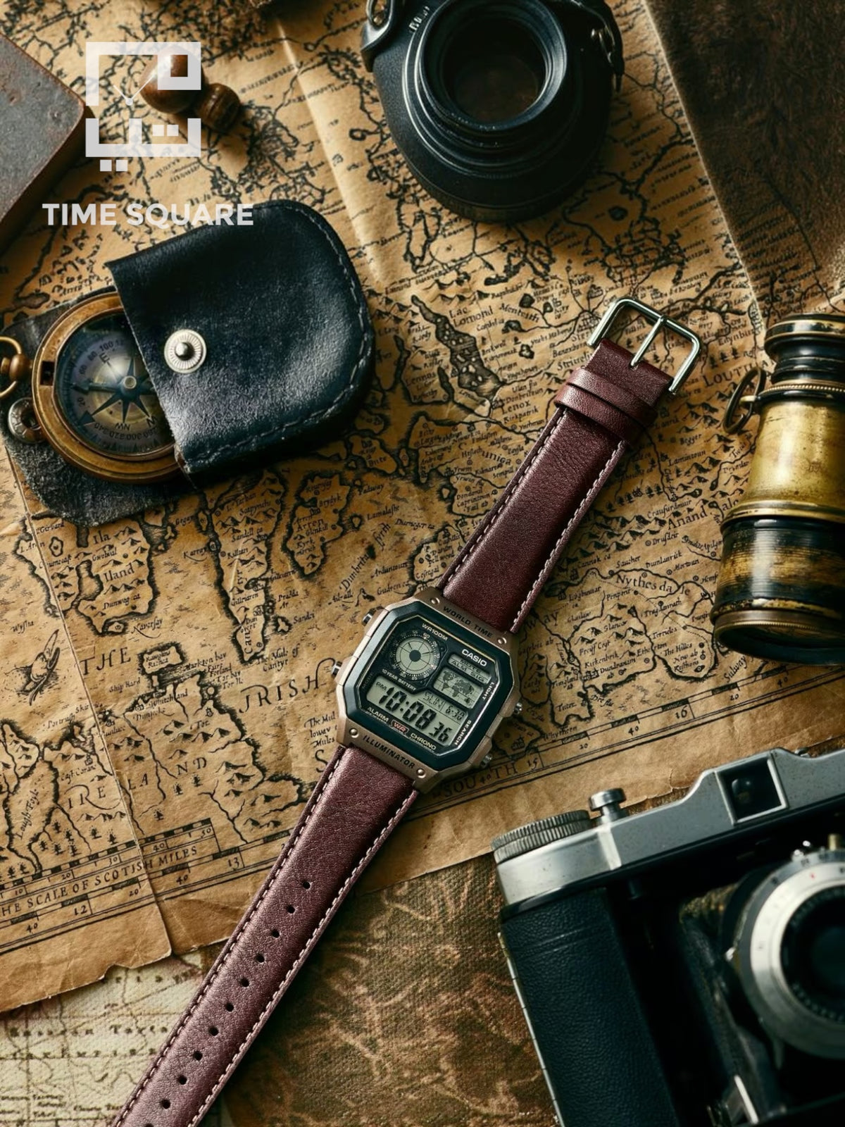 A digital watch with a brown leather strap and silver-toned case, laid diagonally across an antique-style world map surrounded by vintage props including a leather case, compass, camera, and telescope. The TIME SQUARE logo is visible in the top left.