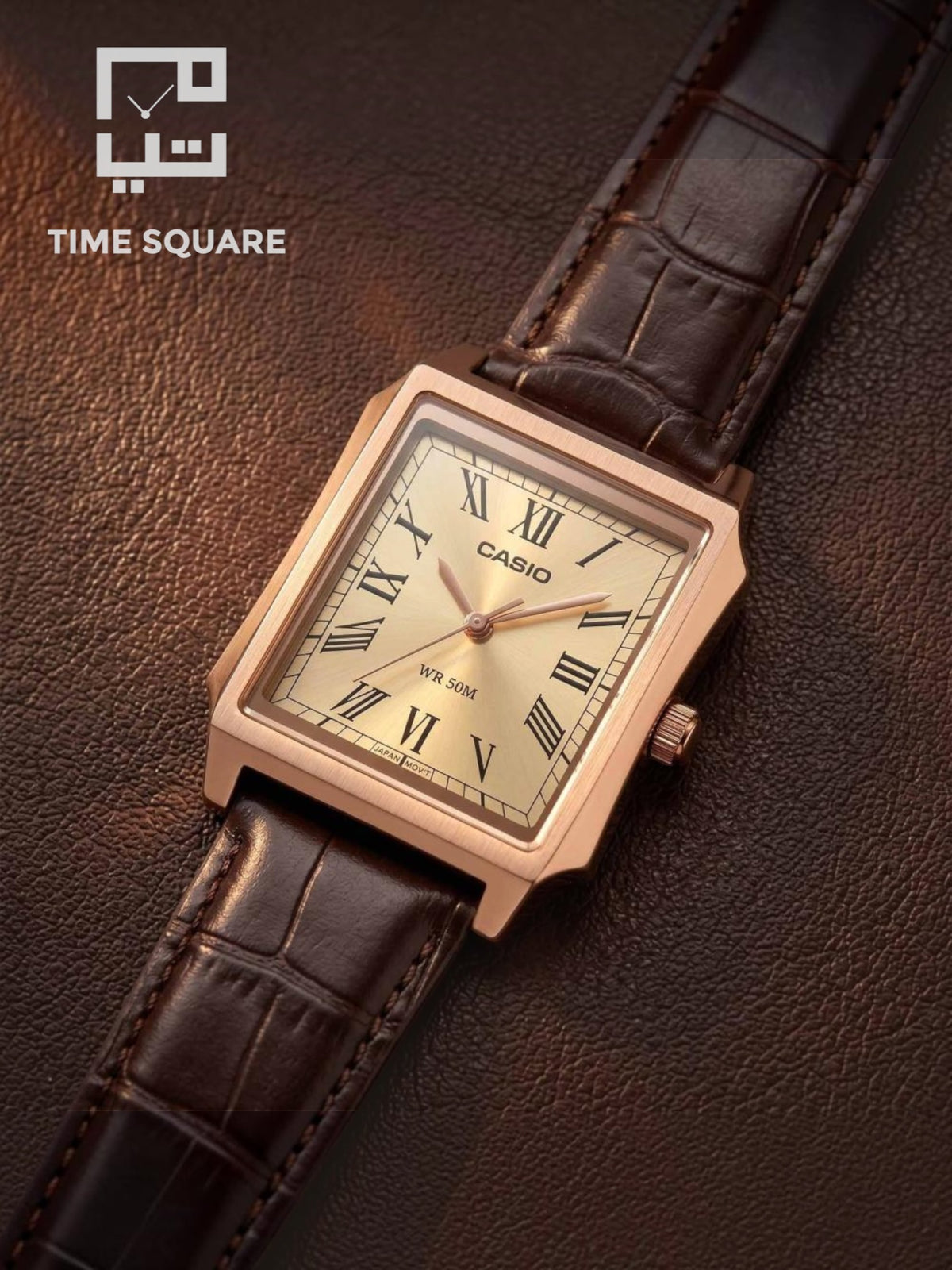 A Casio square analog watch with a rose gold-toned case, Roman numeral dial, and dark brown leather strap, displayed diagonally on a textured brown leather surface. The TIME SQUARE logo is visible in the top-left corner.