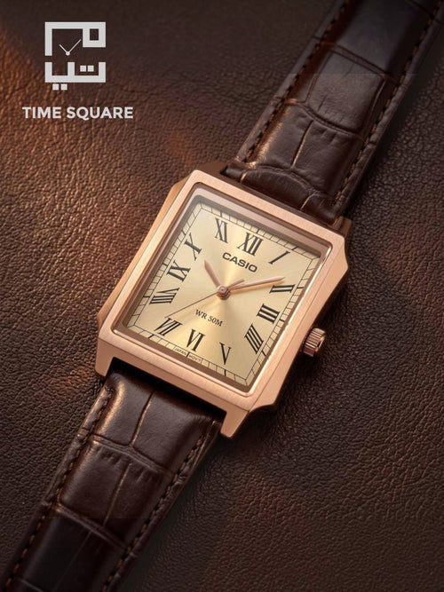 A Casio square analog watch with a rose gold-toned case, Roman numeral dial, and dark brown leather strap, displayed diagonally on a textured brown leather surface. The TIME SQUARE logo is visible in the top-left corner.